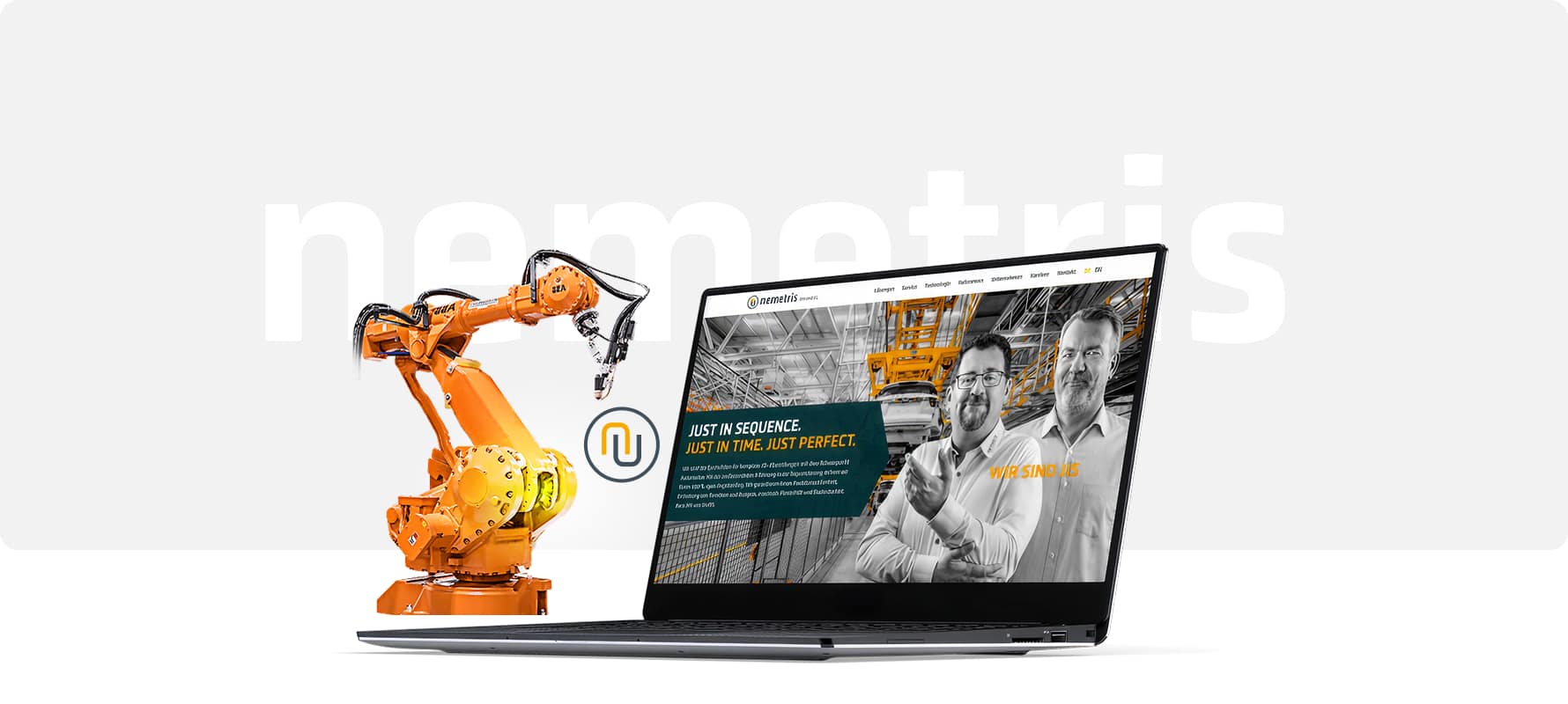 Industrieroboter aus Metall in Orange neben einem schwarzen Laptop mit geöffneter Webseite