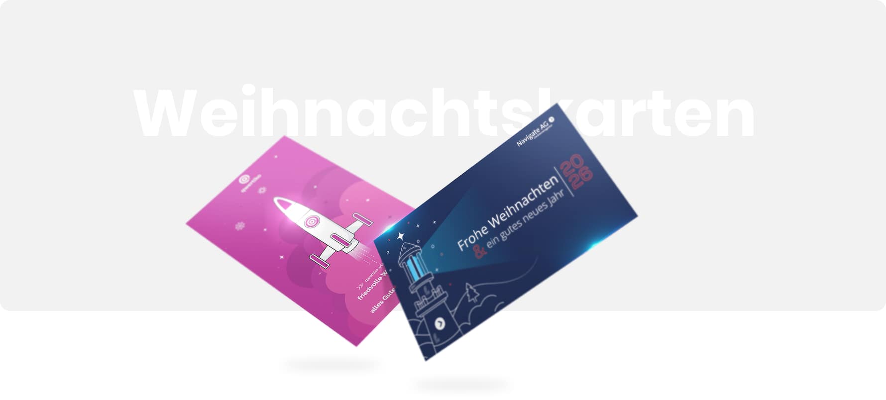 Zwei Weihnachtskarten aus Papier, eine rosa mit Raketenmotiv, eine dunkelblau mit Leuchtturm und Weihnachtsgruß